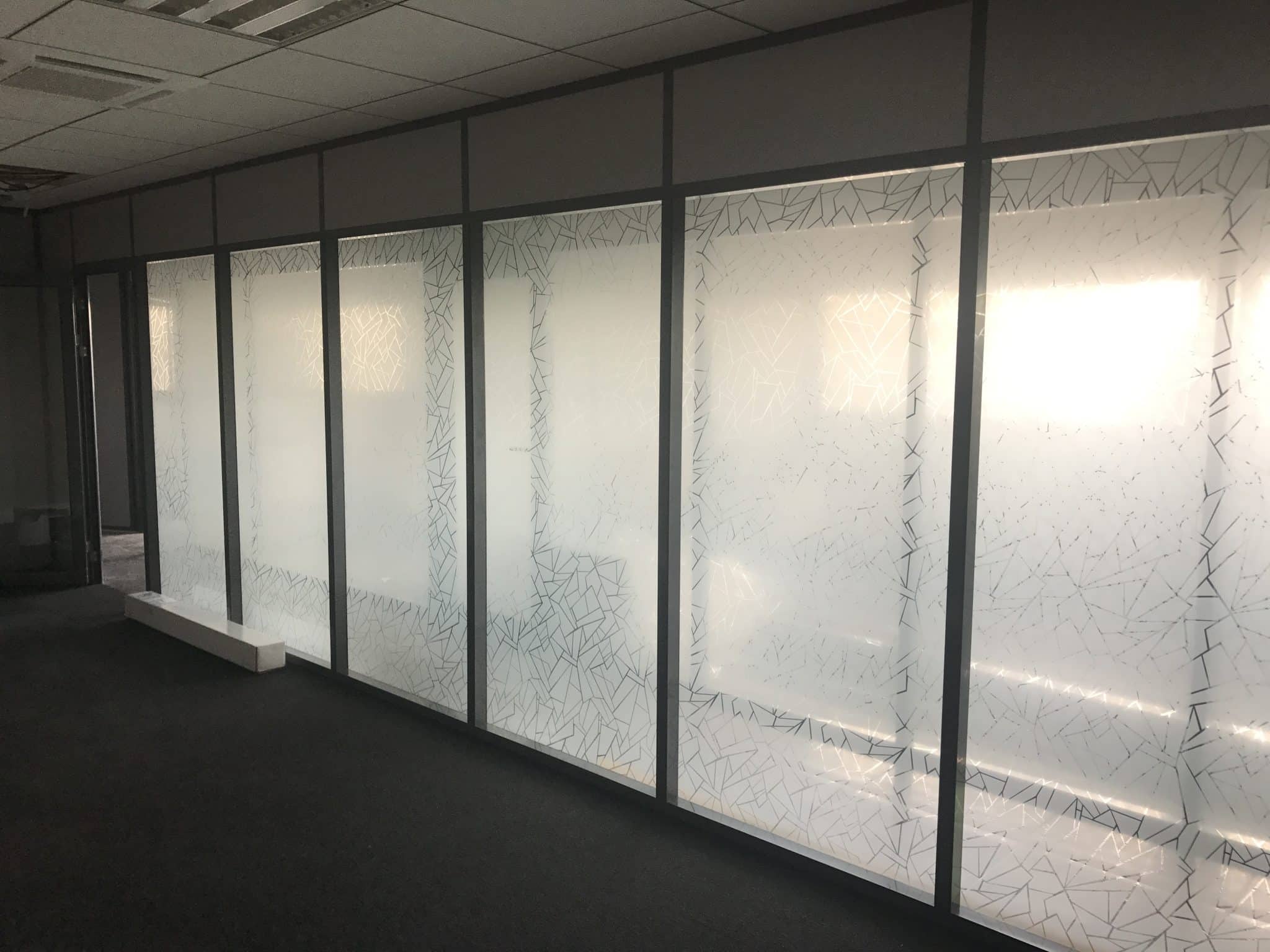 Longue cloison vitrée de bureaux équipée d'un film dépoli qui laisse passer la lumière