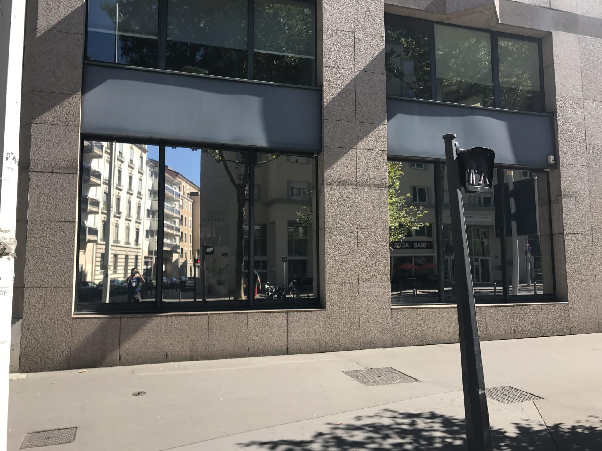 Façade urbaine dont les vitrages équipés d'un film miroir reflètent la rue et les immeubles voisins