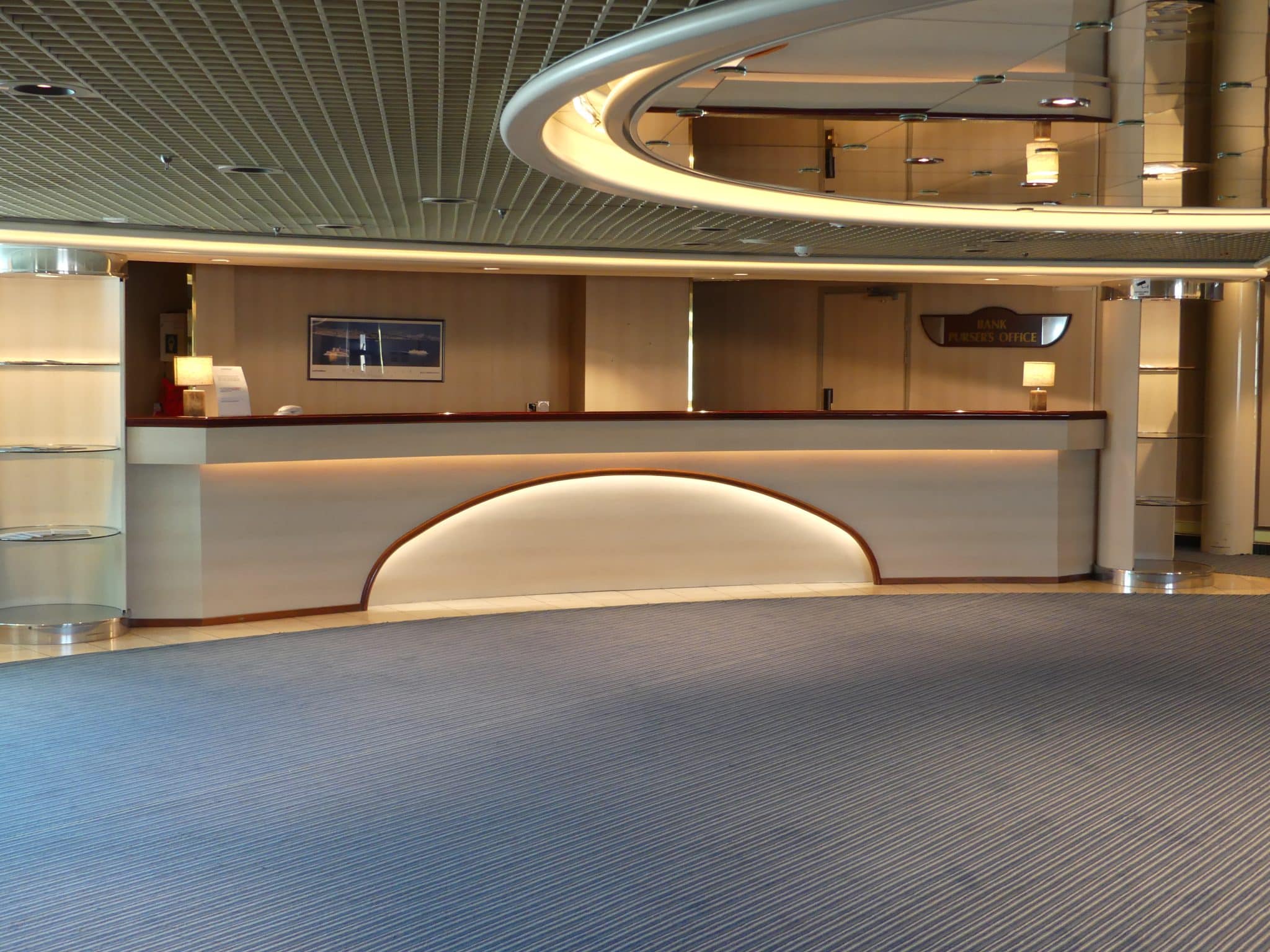 Comptoir d'accueil cintré et panneaux muraux à effet bois clair dans un grand hall