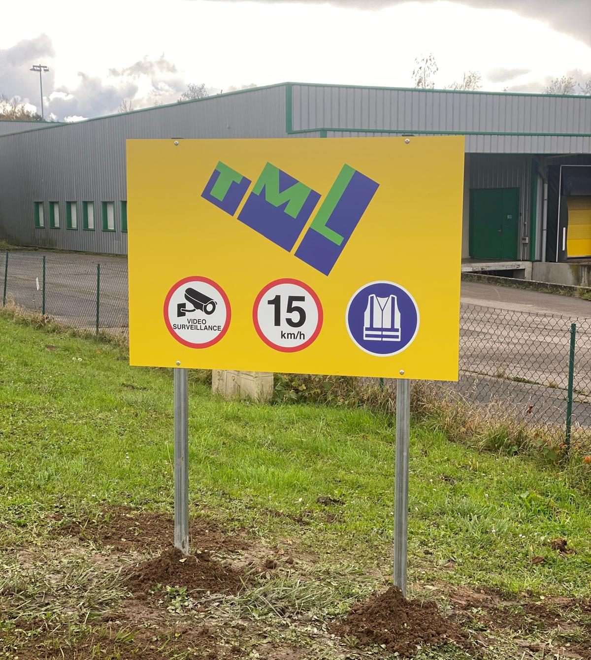 Panneau de site extérieur sur poteaux avec logo d'entreprise et pictogrammes de vidéosurveillance, vitesse limitée et gilet obligatoire