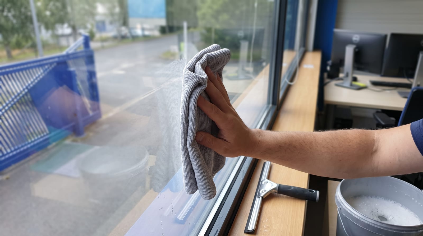 Nettoyage d'une vitre équipée d'un film avec une microfibre et une raclette en caoutchouc