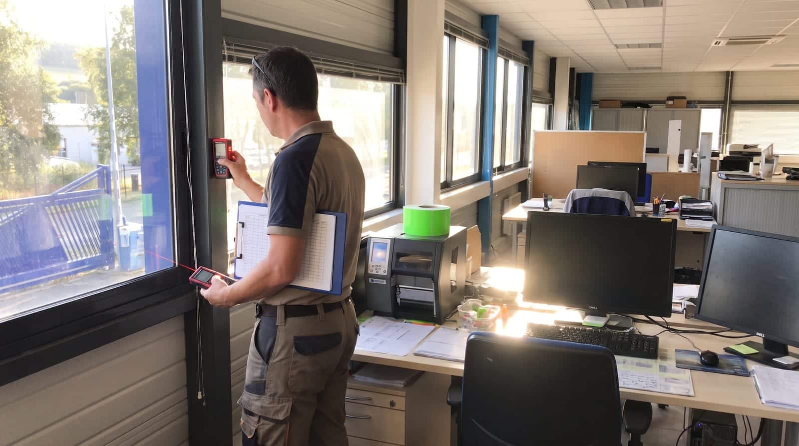 Gestionnaire technique relevant les dimensions d'une fenêtre de bureau exposée au soleil